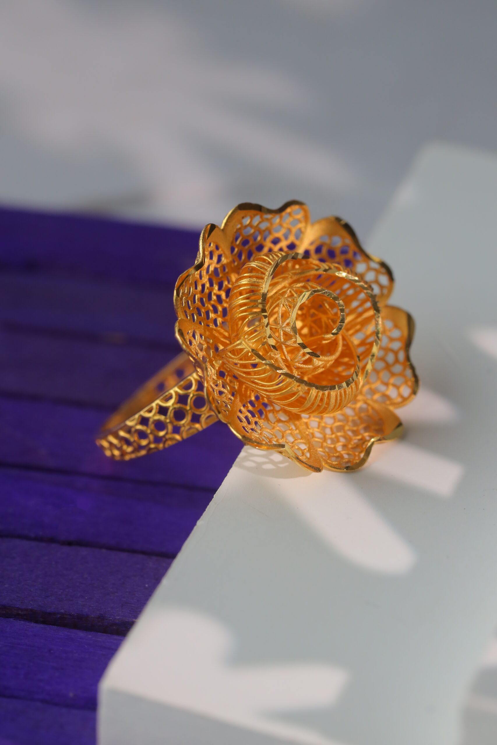 The circular arrangement of the flower on the ring is open on the top, forming a unique and remarkable three-dimensional look that was modeled after the appearance of a rose at different stages of bloom. The petals of the flower’s enchantment feature strands of wires that are intricately arranged, while the body shines in rich gold tones that are plush. Alternatively, as a signature statement, this Kuwaiti Gold Ring will complement any style or look effortlessly.
