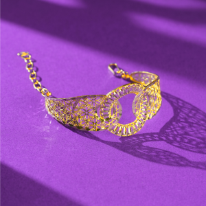 22KT gold bracelet with two overlapping rings, flower-pattern cut-out band, faceted edges and a link chain.