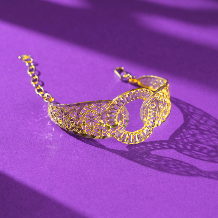 22KT gold bracelet with two overlapping rings, flower-pattern cut-out band, faceted edges and a link chain.