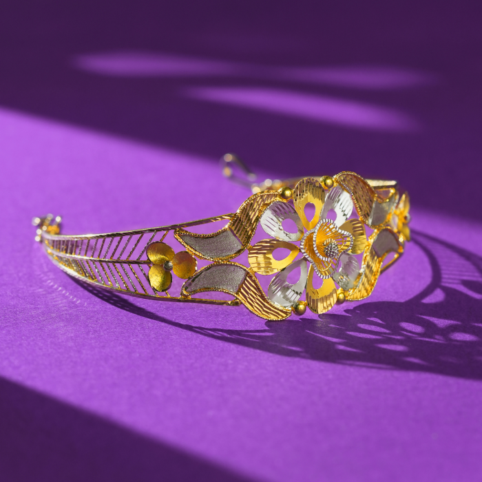 22KT gold bracelet with a large flower of teardrop cut-out petals in yellow and white tones on a slim slanted-line band.
