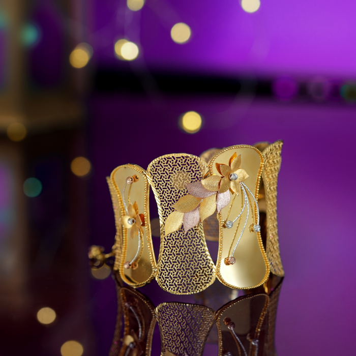 22KT gold bracelet with a cut-out centre panel, petal flower and hanging beads on beaded glossy panels.