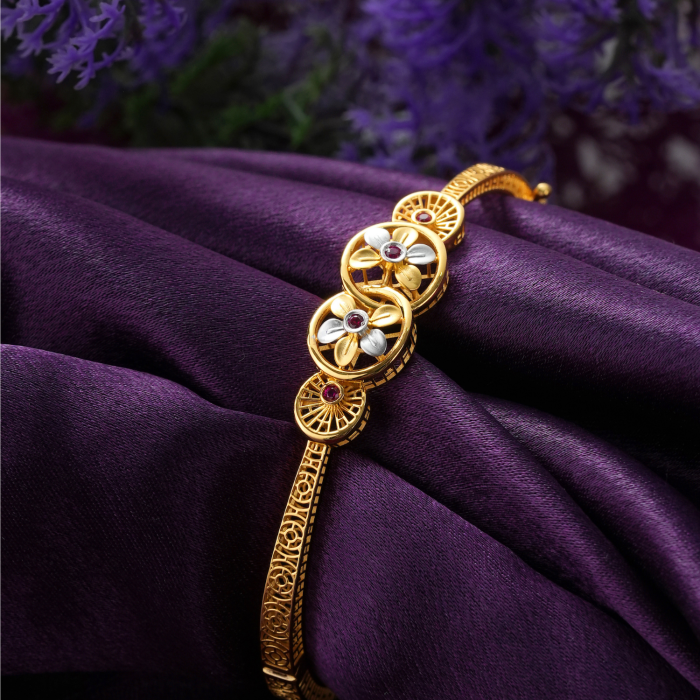 18KT gold bracelet with two flower rings in yellow gold and rhodium, red stones and spoked discs.