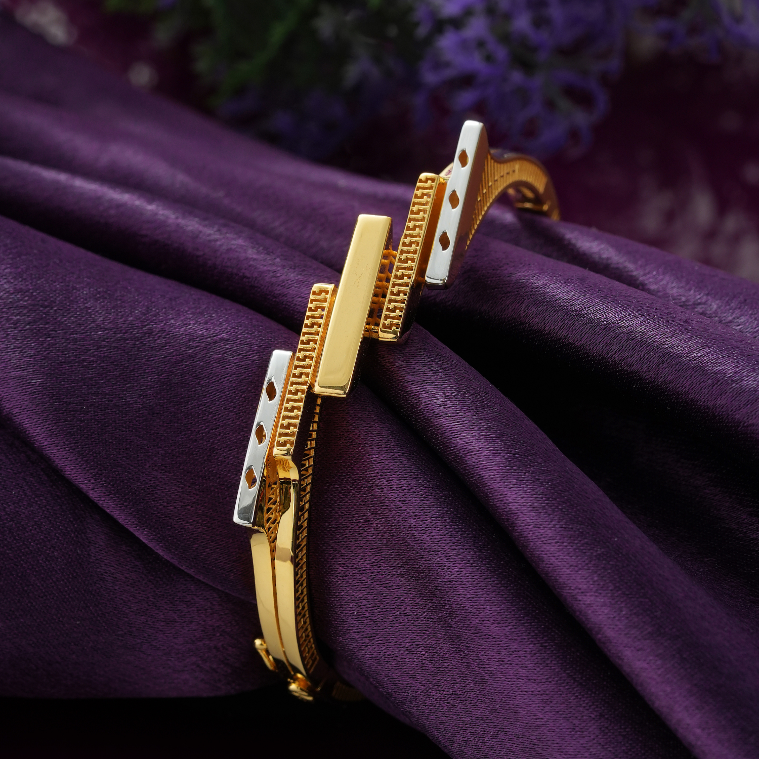 18KT gold bracelet with five upright bars in glossy gold, rhodium and key-pattern gold on a slim woven-texture band.