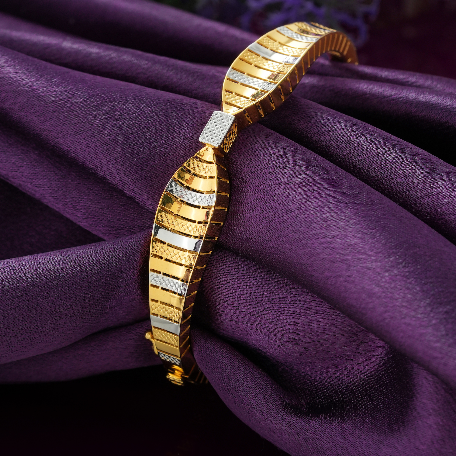 18KT gold bracelet with a wavy band of glossy, diamond-cut and rhodium strips and a small grid-textured square.