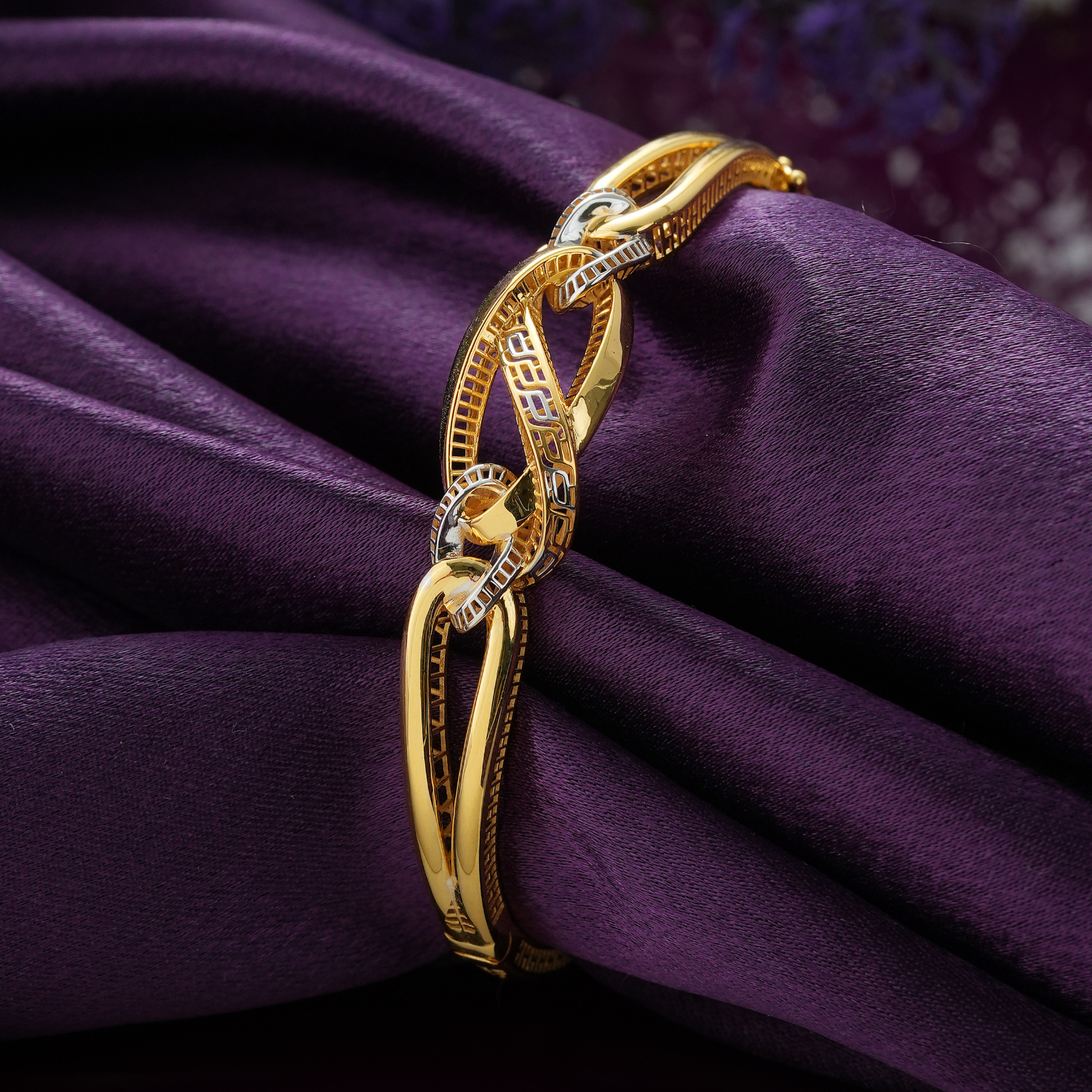 18KT gold bracelet with interlocking glossy oval loops, a key-pattern centre and rhodium-rimmed links.
