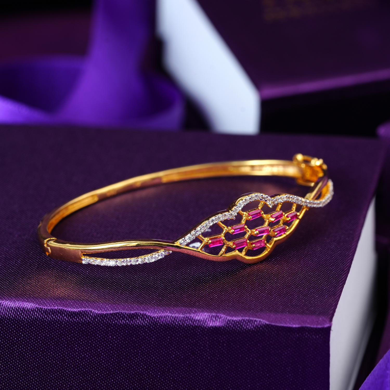 18KT gold bracelet with a wavy panel of pink stones, white stone border and a slim gold band.