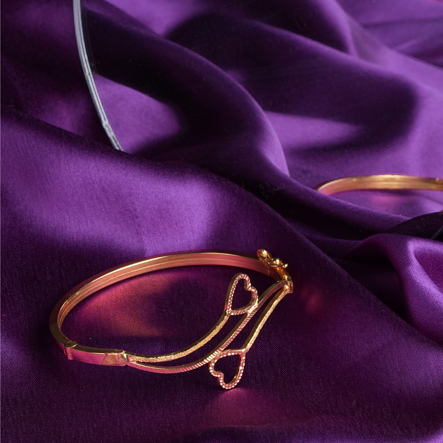 Heartstrings 18kt gold bracelet by Taqwa Jewellers with an open, intertwined heart design and dual-finish polished and textured band.