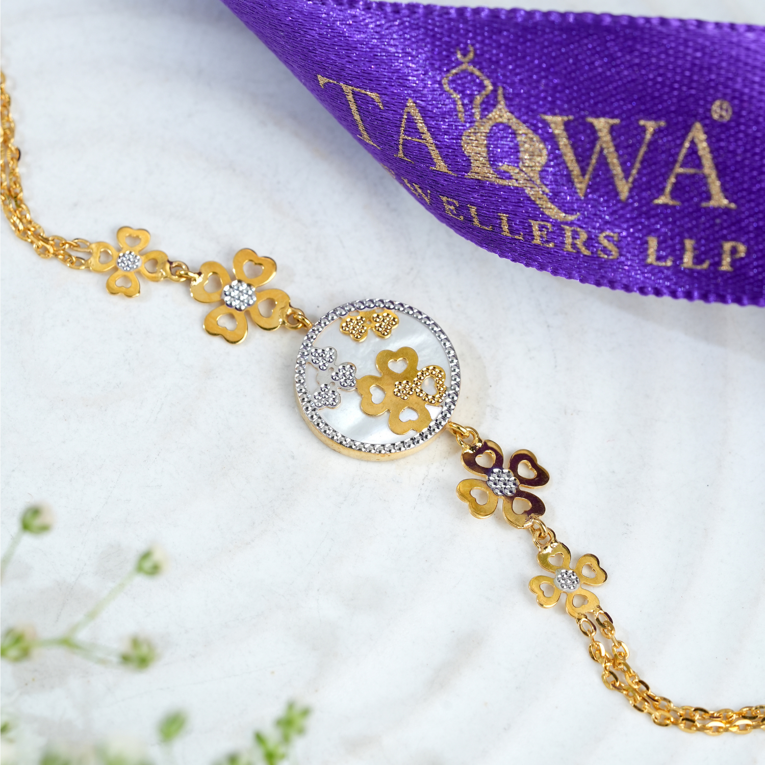Quadglow 18kt gold bracelet by Taqwa Jewellers with four-heart clover clusters on a pearled medallion and dual-tone chain links.