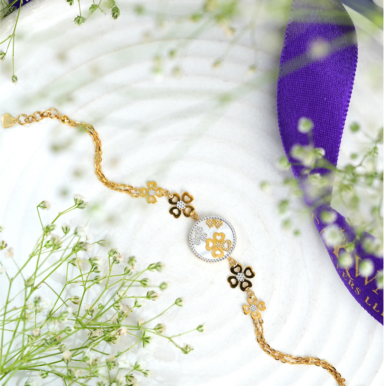 Quadglow 18kt gold bracelet by Taqwa Jewellers with four-heart clover clusters on a pearled medallion and dual-tone chain links.