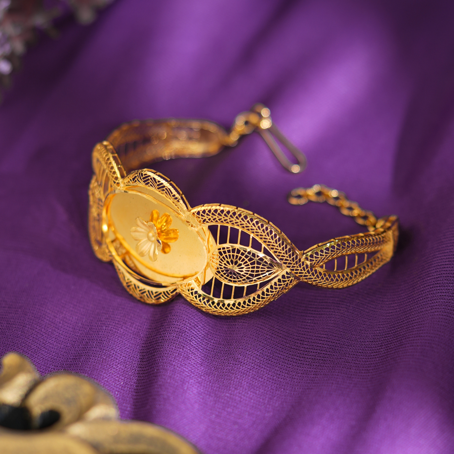 Halo Embrace 18kt gold bracelet by Taqwa Jewellers with a carved flower centre, gold lattice detailing and wave-shaped openwork links.