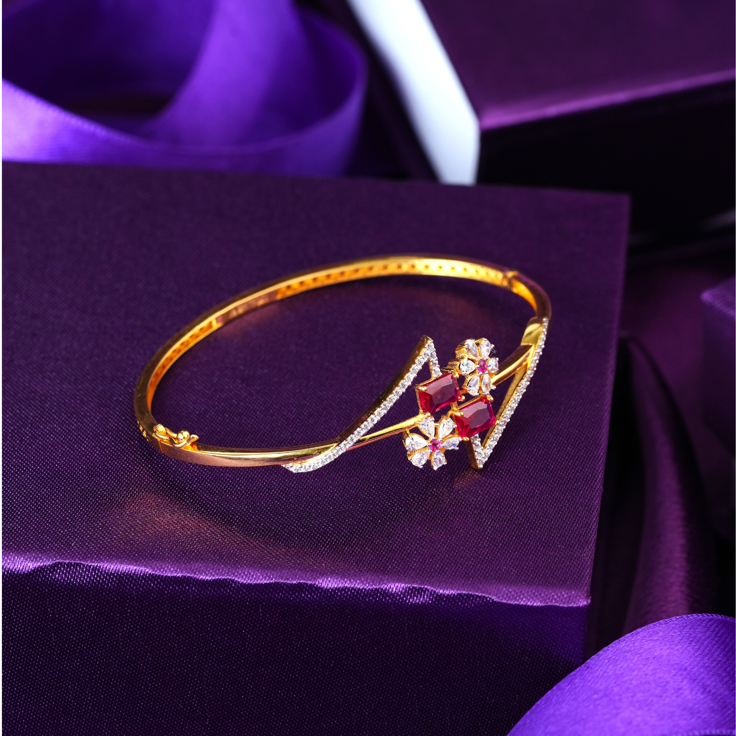 18KT gold bracelet with two pink square-cut stones, white stone flowers and zigzag stone lines on a slim band.