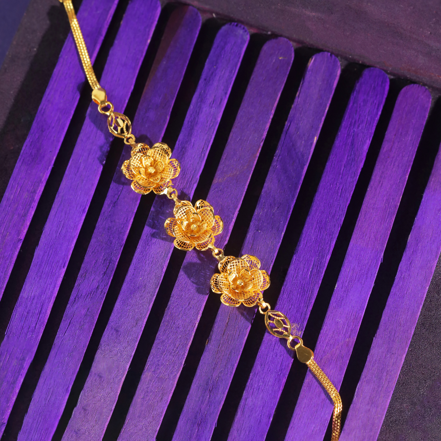 22KT gold bracelet with three layered mesh flowers linked in a row and a flat chain on both sides.