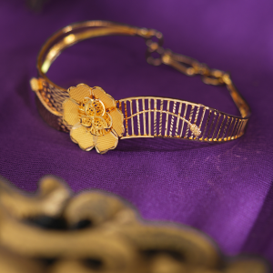 Bloomline 18kt gold bracelet by Taqwa Jewellers with a layered floral centre and curved open gold lines.