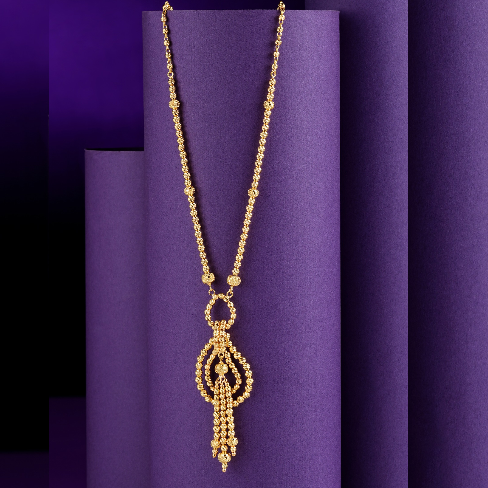 Eterna Knot 18KT yellow gold chain with decorative links, an interlocking loop and teardrop-shaped pendant, and multiple dangling gold elements by Taqwa Jewellers.