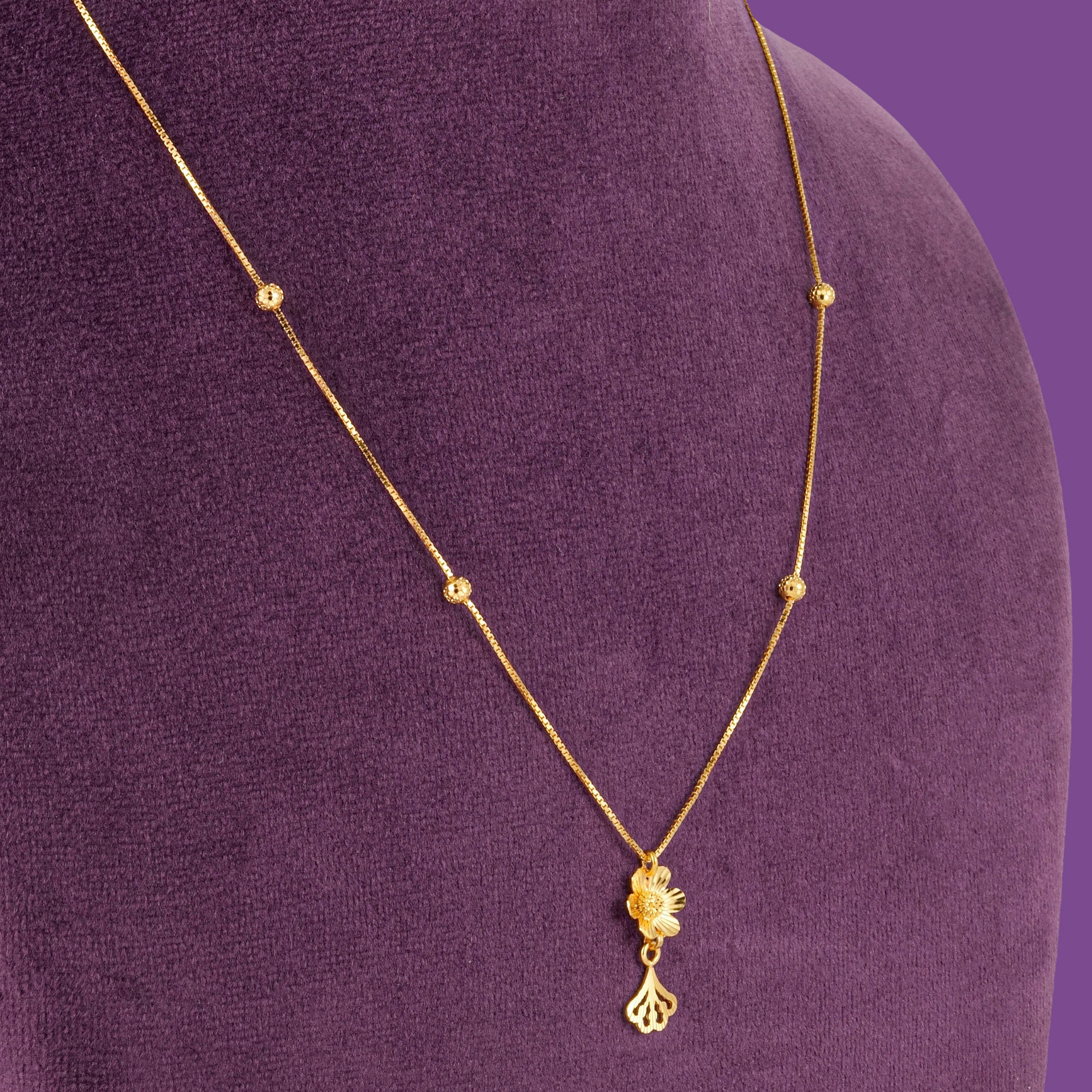 A 22KT gold box chain with a five-petal flower pendant and fan-shaped drop, by Taqwa Jewellers.